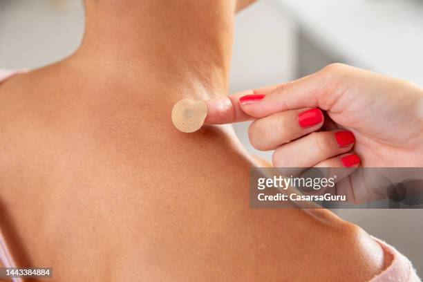 applying magnetic acupressure patches for body and pain relief on woman's shoulder - applying bandaid stock pictures, royalty-free photos & images
