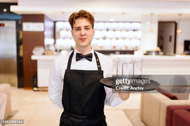 waiter serving water in a hotel lobby - kelner stockfoto's en -beelden
