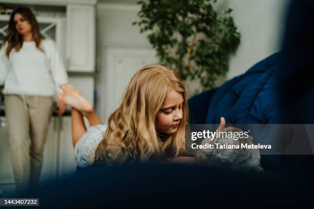 dysfunctional family, only friend is a cat. little girl lying with domestic gray cat on a sofa against mother - ignoring stock pictures, royalty-free photos & images