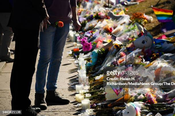 Mourner brings flowers to leave at the growing memorial where hundreds of flowers, balloons, signs and remembrances have been left for the victims of...