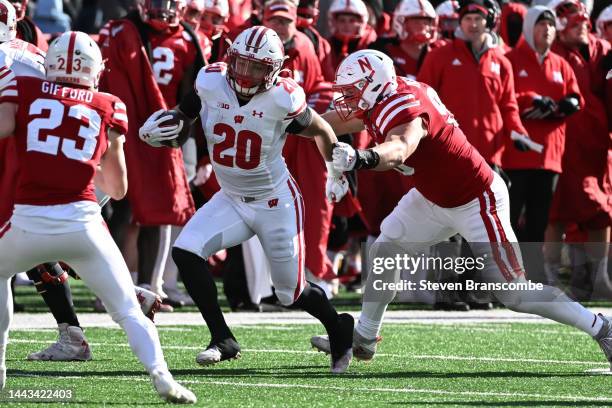 Running back Isaac Guerendo of the Wisconsin Badgers tries to run from defensive back Isaac Gifford of the Nebraska Cornhuskers during the second...