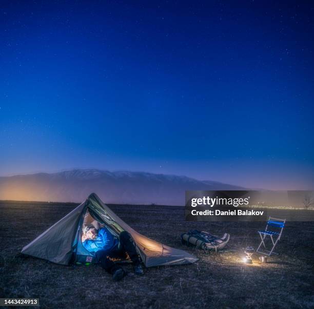 mature tourist using phone in tent at night. camping in mountain alone in nature. - one man only stock pictures, royalty-free photos & images