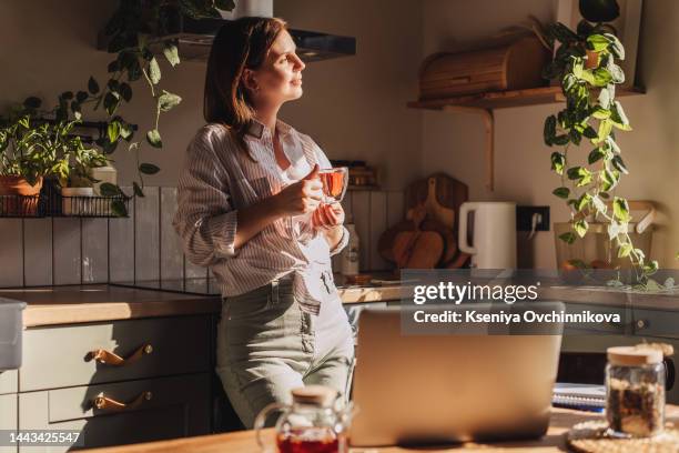 young happy woman drinking coffee on the kitchen in the morning. - relaxation stock-fotos und bilder