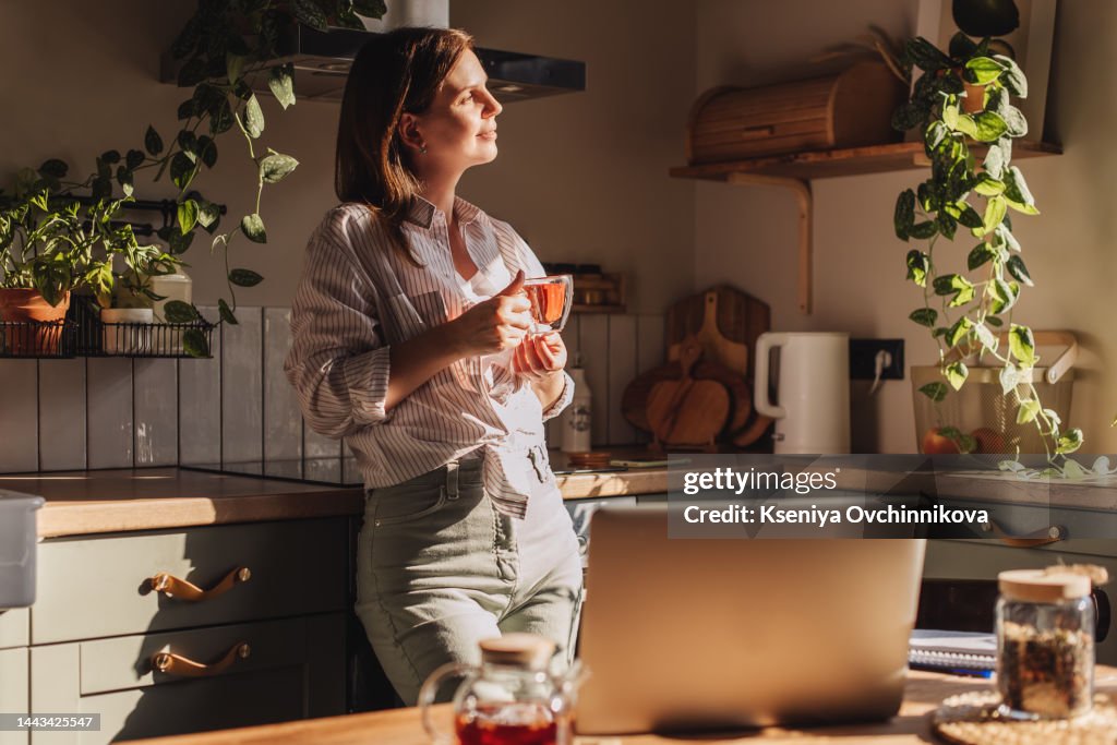 Young happy woman drinking coffee on the kitchen in the morning.