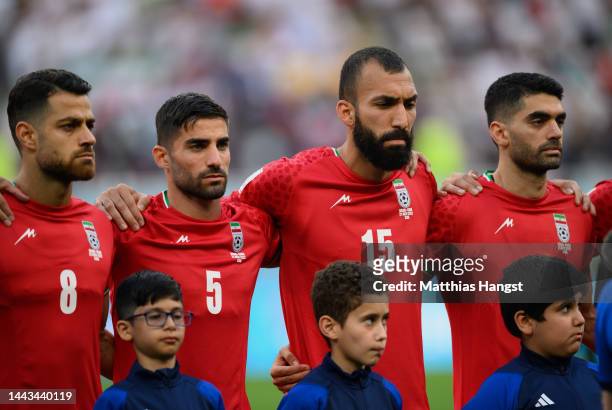 Morteza Pouraliganji, Milad Mohammadi and Roozbeh Cheshmi of IR Iran line up for the national anthem prior to the FIFA World Cup Qatar 2022 Group B...