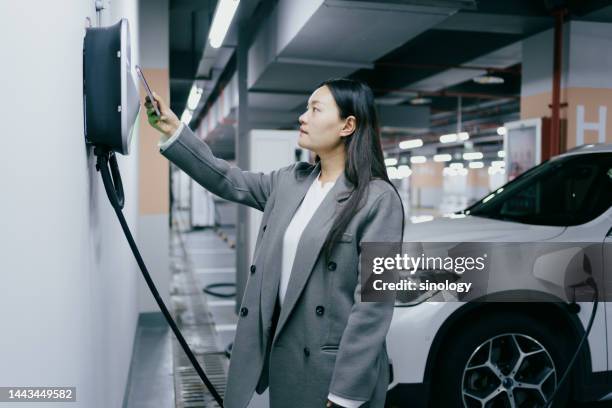 asian woman is paying to charge her electric car with her smartphone - animals charging stock pictures, royalty-free photos & images