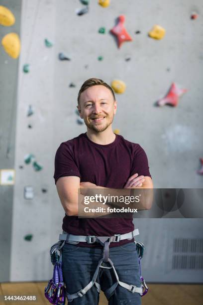 young male climber standing against climbing wall - bergbeklimartikelen stockfoto's en -beelden