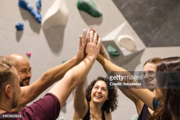 happy group of people high fiving at rock climbing center - sports team high five stock pictures, royalty-free photos & images