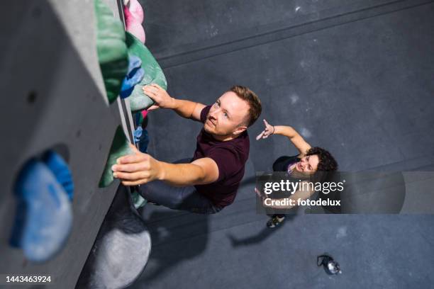 man on the bouldering training with female instructor at sport climbing gym - climbers stockfoto's en -beelden