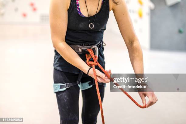 female climber ties a safety knot on the harness before climbing the artificial wall - zekeren stockfoto's en -beelden