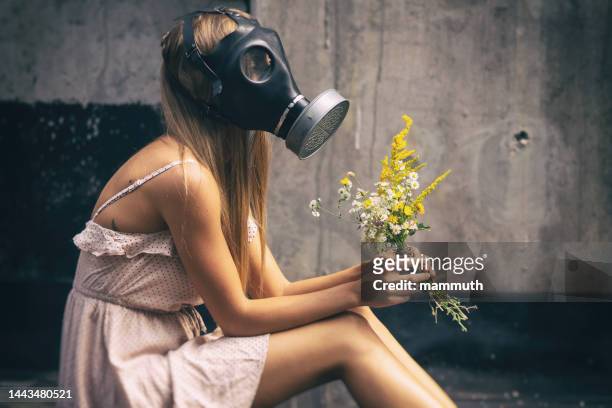 young woman in gas mask with flowers - hayfever stockfoto's en -beelden