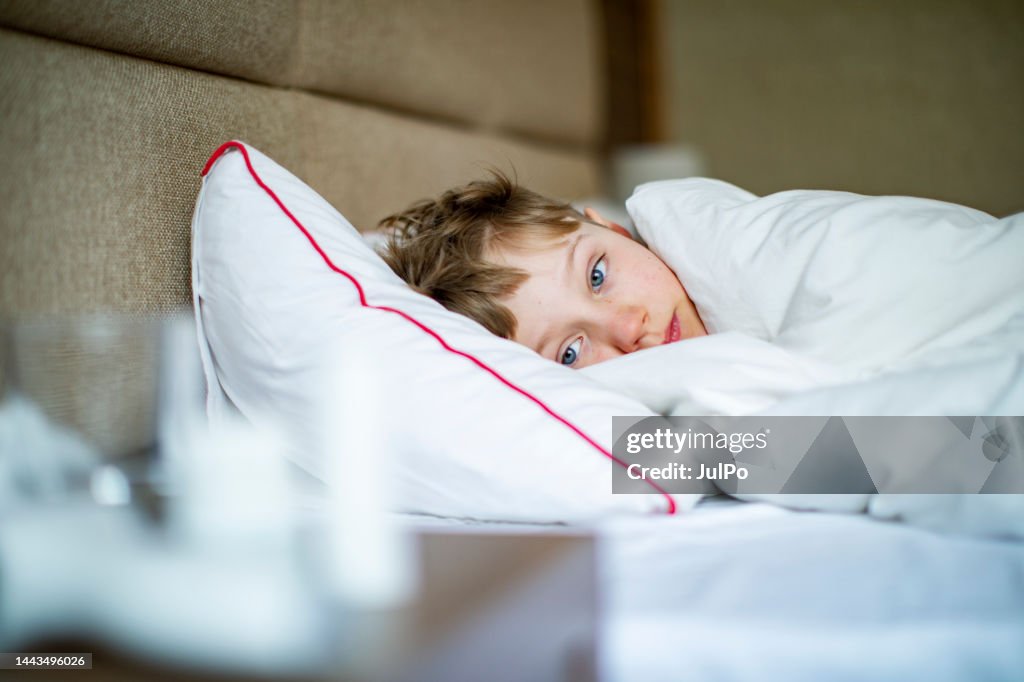 School age boy laying in bed with a flu