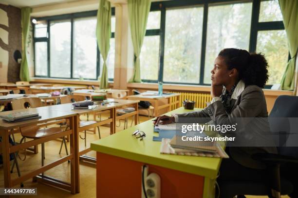 thoughtful african american teacher working in the classroom. - teacher grading paper stock pictures, royalty-free photos & images