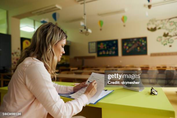 female teacher grading exams in the classroom. - grading stock pictures, royalty-free photos & images