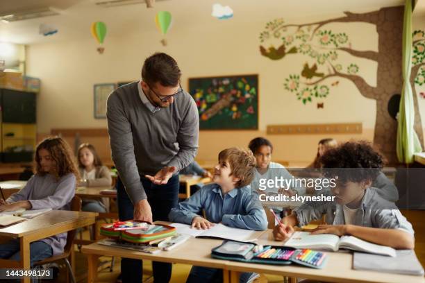 insegnante maschio felice che assiste uno scolaro in classe. - white male professor foto e immagini stock