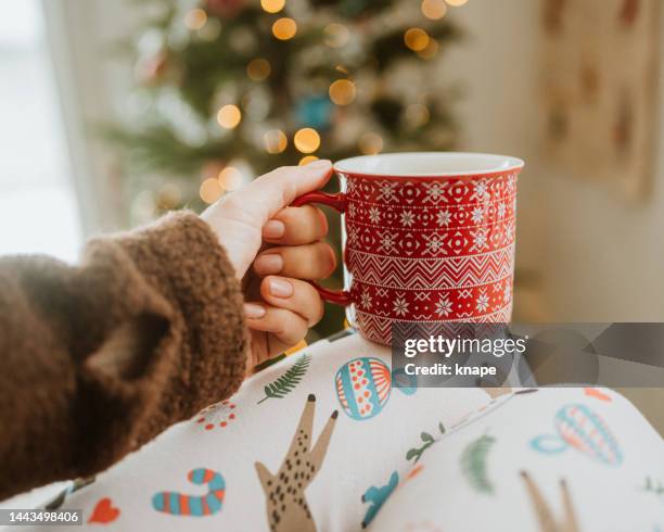 drinking christmas coffee infront of ornate christmas tree - christmas mug stock pictures, royalty-free photos & images