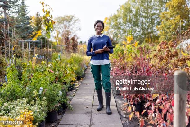 portrait of african woman garden center worker with digital tablet - shifting cultivation stock-fotos und bilder