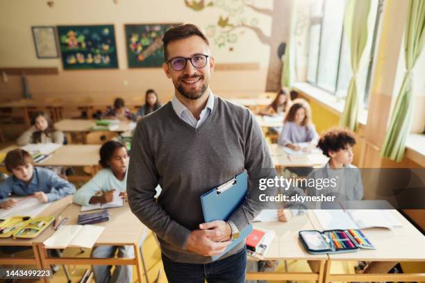 happy elementary teacher in front of his students in the classroom. - teacher in front of class stock pictures, royalty-free photos & images