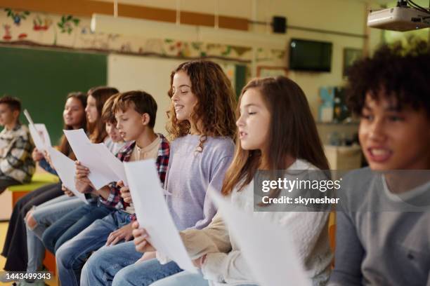 schulkinder üben mit noten in einer klasse in der schule. - gesangsunterricht stock-fotos und bilder