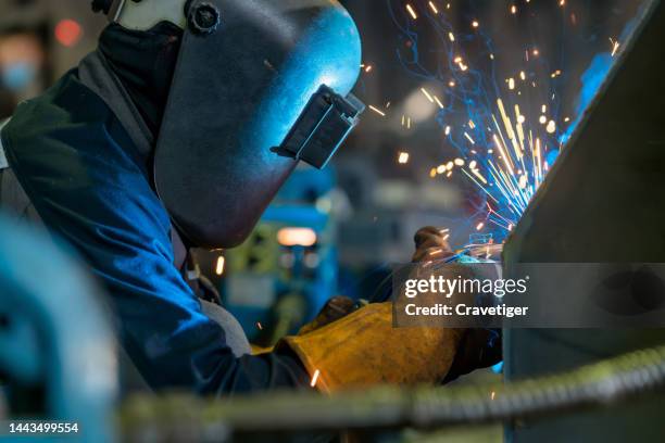 close-up of a welder wielding sparks . welder welding metal in workshop - obrero-siderúrgico fotografías e imágenes de stock