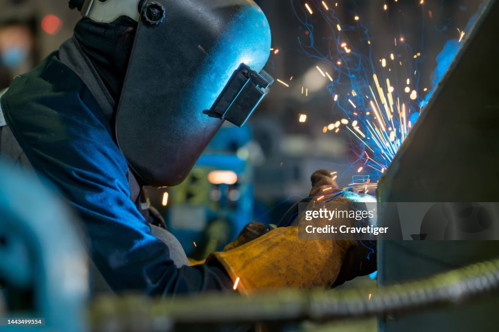 Close-up of a welder wielding sparks . Welder Welding Metal In Workshop