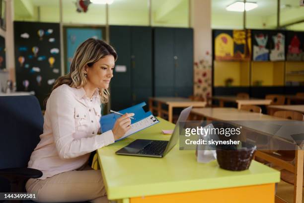 young female teacher working in the classroom. - teacher desk stock pictures, royalty-free photos & images