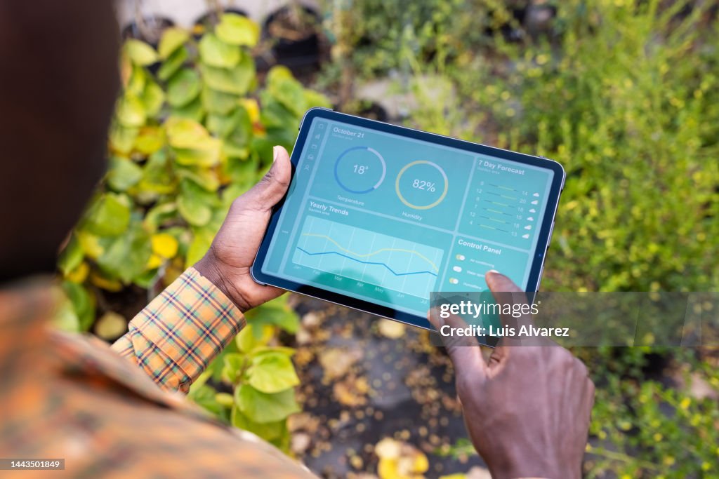Man updating plants growth on digital tablet app in garden center