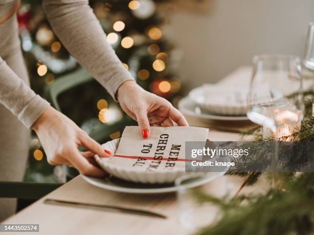 woman setting the christmas table preparing for dinner party - tafel dekken stockfoto's en -beelden