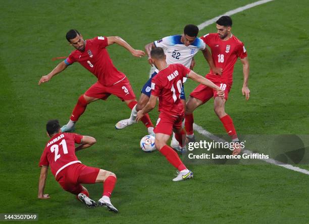 Jude Bellingham of England battles for possession with Ehsan Hajisafi, Majid Hosseini and Ali Karimi of IR Iran during the FIFA World Cup Qatar 2022...