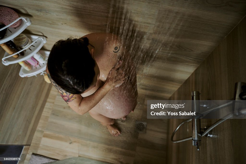 Middle-aged pregnant under the shower water