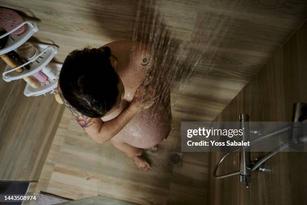 middle-aged pregnant under the shower water - woman in shower tattoo stock pictures, royalty-free photos & images