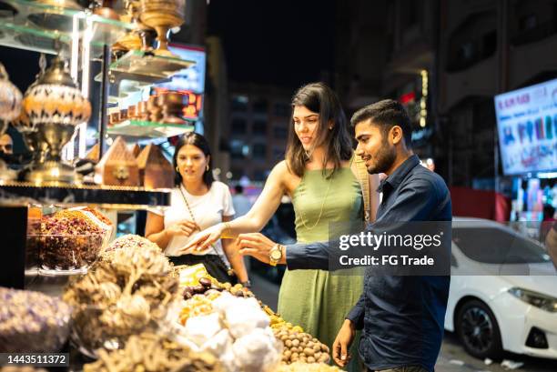 salesman talking and selling ingredients to tourists in a street market - bazaar stockfoto's en -beelden