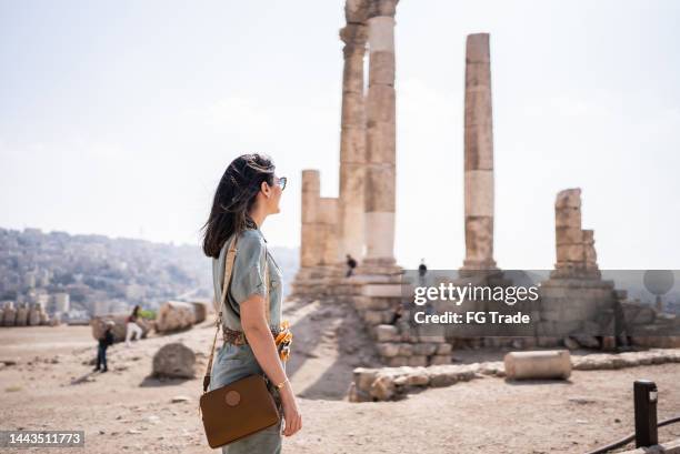 mid adult woman tourist admiring antique columns in amman city, jordan - amman stockfoto's en -beelden