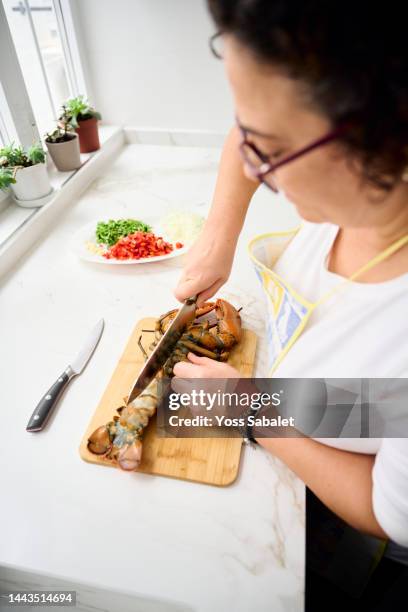 woman cutting a lobster to make paella - ingredientes stock-fotos und bilder