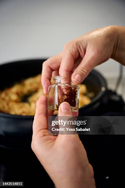 woman picking saffron on a branch to add to the paella - saffron stock pictures, royalty-free photos & images