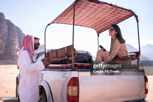 middle eastern guide talking to female tourist in a car around desert - jordan stock pictures, royalty-free photos & images