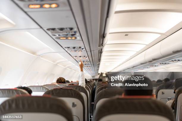 person calling for help on airplane from traveling passengers - airplane interior stockfoto's en -beelden