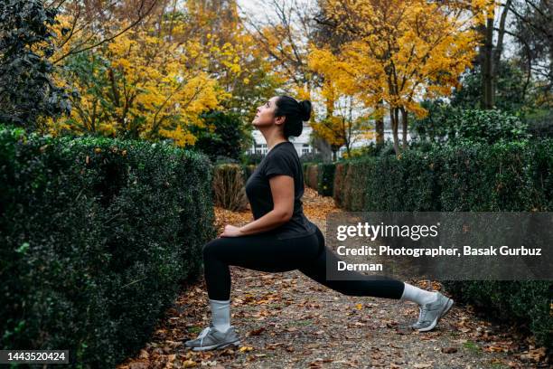 woman stretching in park in a beautiful autumn day - hips stock-fotos und bilder