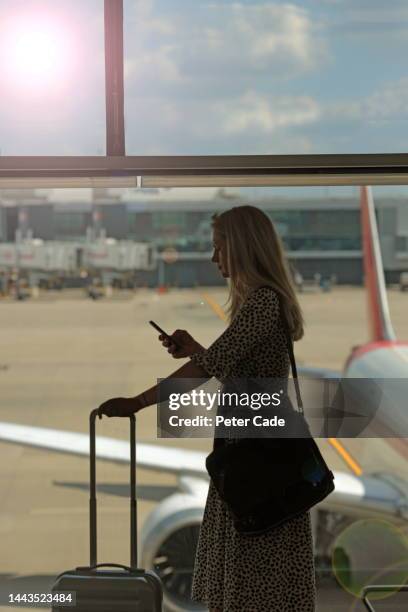 woman waiting at airport for flight - woman blond looking left window stockfoto's en -beelden