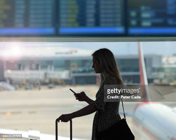woman waiting at airport for flight - woman blond looking left window stockfoto's en -beelden