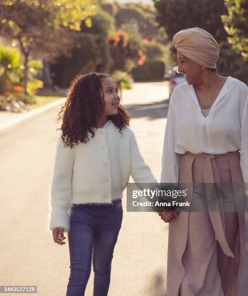 grandmother and her granddaughter walking on the street, during sunset - fashionable grandma stock pictures, royalty-free photos & images