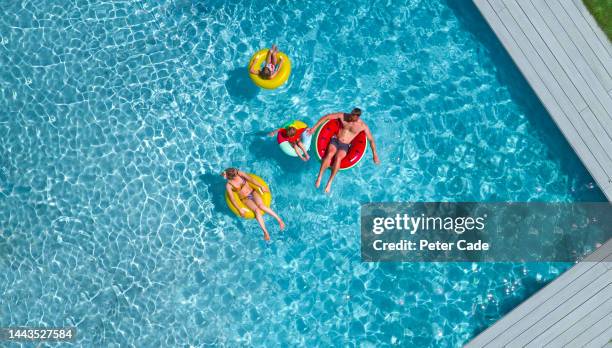 family in pool. aerial picture - boy-in-inner-tube-pool stock pictures, royalty-free photos & images