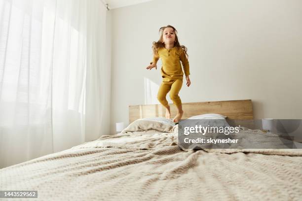 carefree girl having fun while jumping on a bed. - children jumping bed stock pictures, royalty-free photos & images