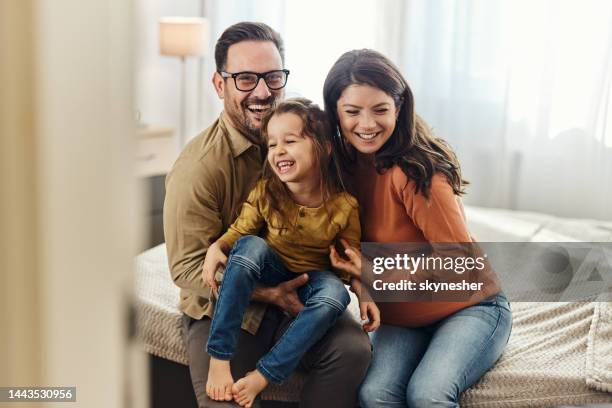 young cheerful family having fun in bedroom. - cheerful family stock pictures, royalty-free photos & images