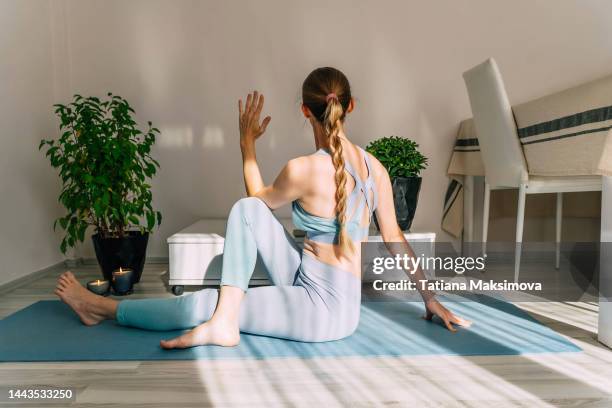 mid adult woman doing yoga at home on a sunny day. indoor plants in the background. - pilates stockfoto's en -beelden