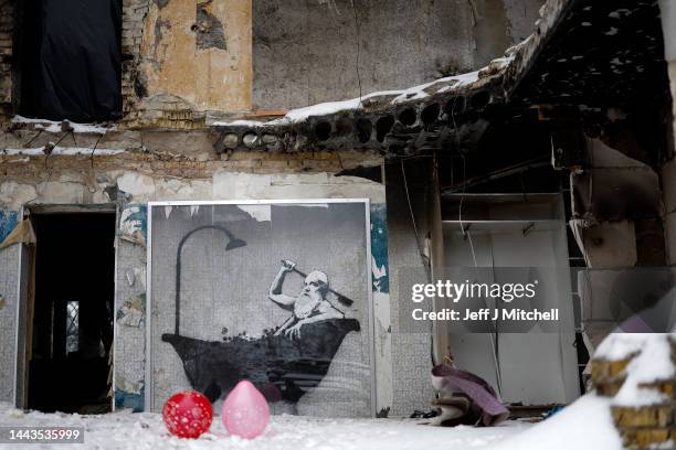 Members of public queue for food beside a picture by graffiti artist Banksy on a the wall of a destroyed building on November 22, 2022 in Horenka,...