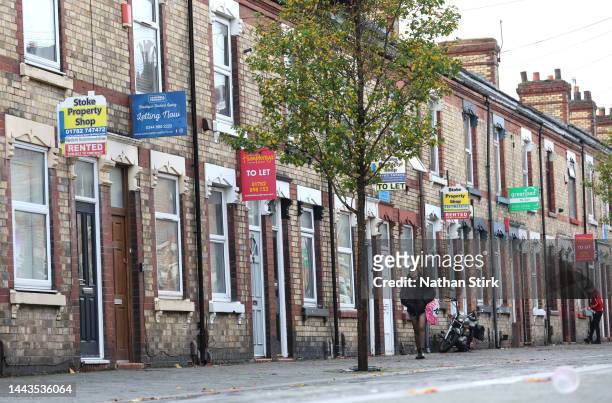 Lady walks past a street of terraced houses advertising properties are Rented or To Let on November 22, 2022 in Stoke-on-Trent, England.