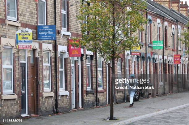 Lady walks past a street of terraced houses advertising properties are rented or to let on November 22, 2022 in Stoke-on-Trent, England.