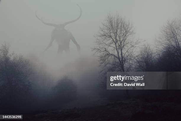 a fantasy concept of a horned god like monster. looking across a forest on a spooky foggy, winters day. - devil stock pictures, royalty-free photos & images
