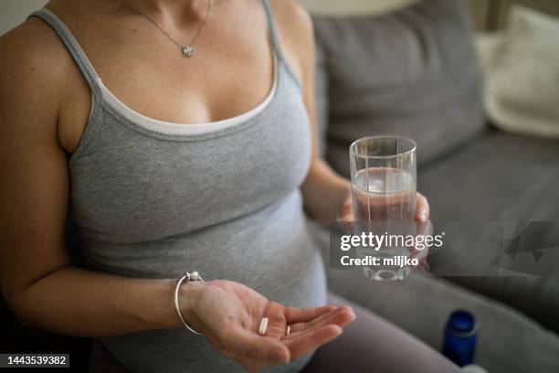 pregnant woman taking a medicine or nutritional supplement - nutritional supplement stockfoto's en -beelden